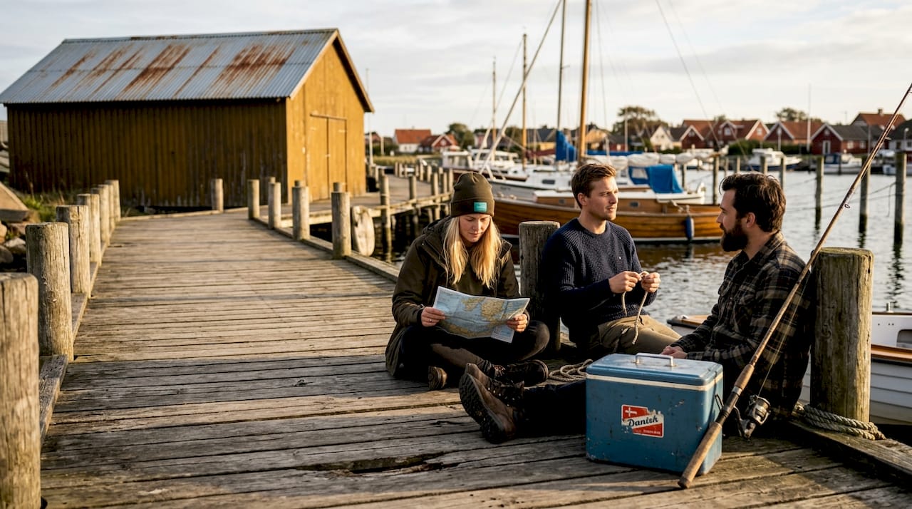 Venner hygger sig på bådebroen i en dansk kysthavn