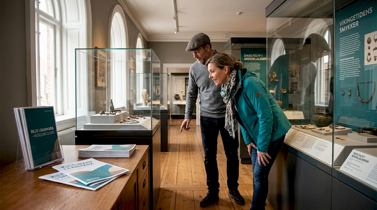 Et par går rundt og udforsker spændende genstande på museet sammen