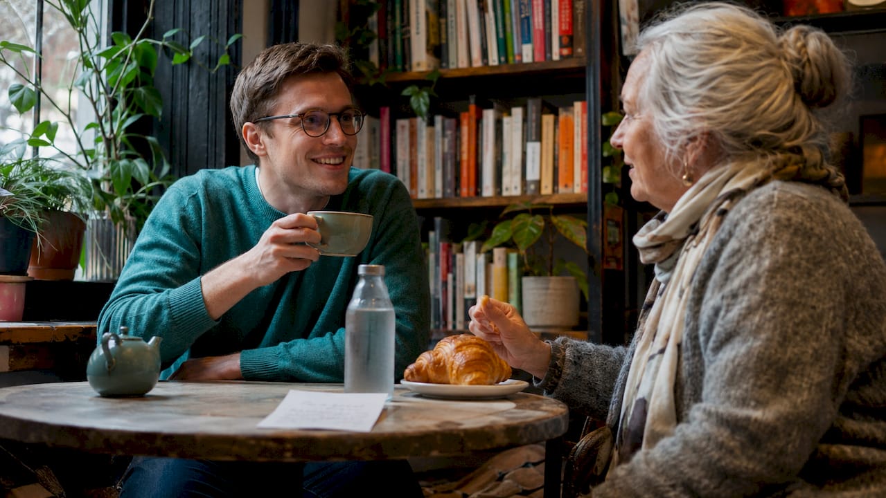 Two friends are sitting and chatting over a cup of coffee at a cozy café in Copenhagen.