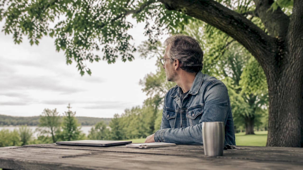 En mand sidder ved et cafébord og holder øje med prisalarmer på sin bærbare computer.