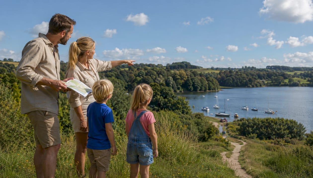En familie nyder udsigten over kysten, mens de sammen studerer et kort.
