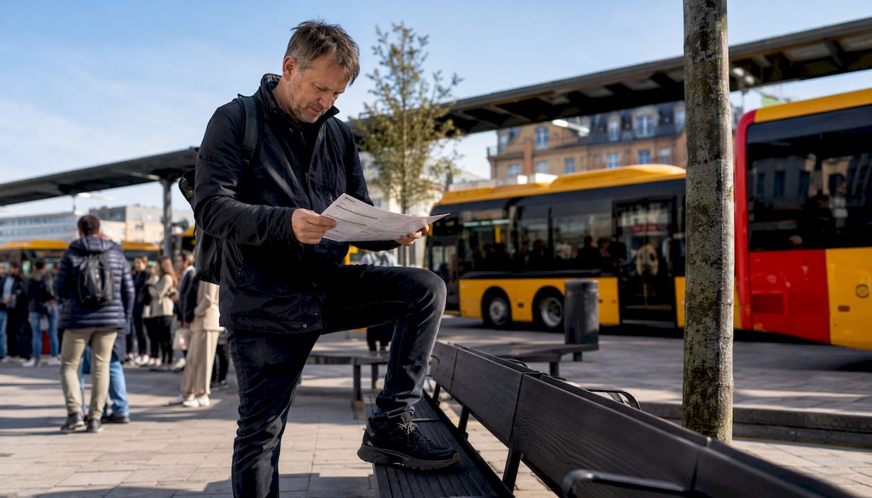 En rejsende står på perronen og tjekker togafgangene på tavlen.