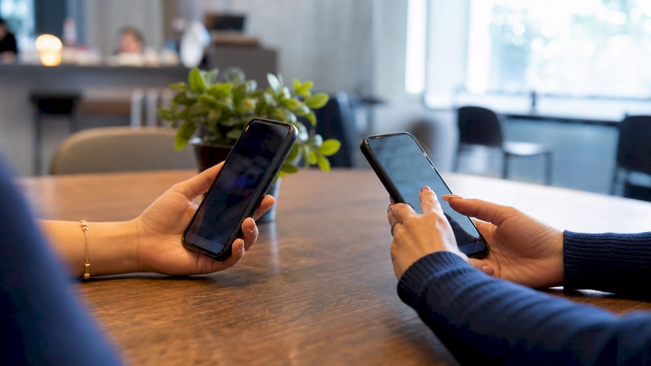 Hands holding phones comparing shopper types