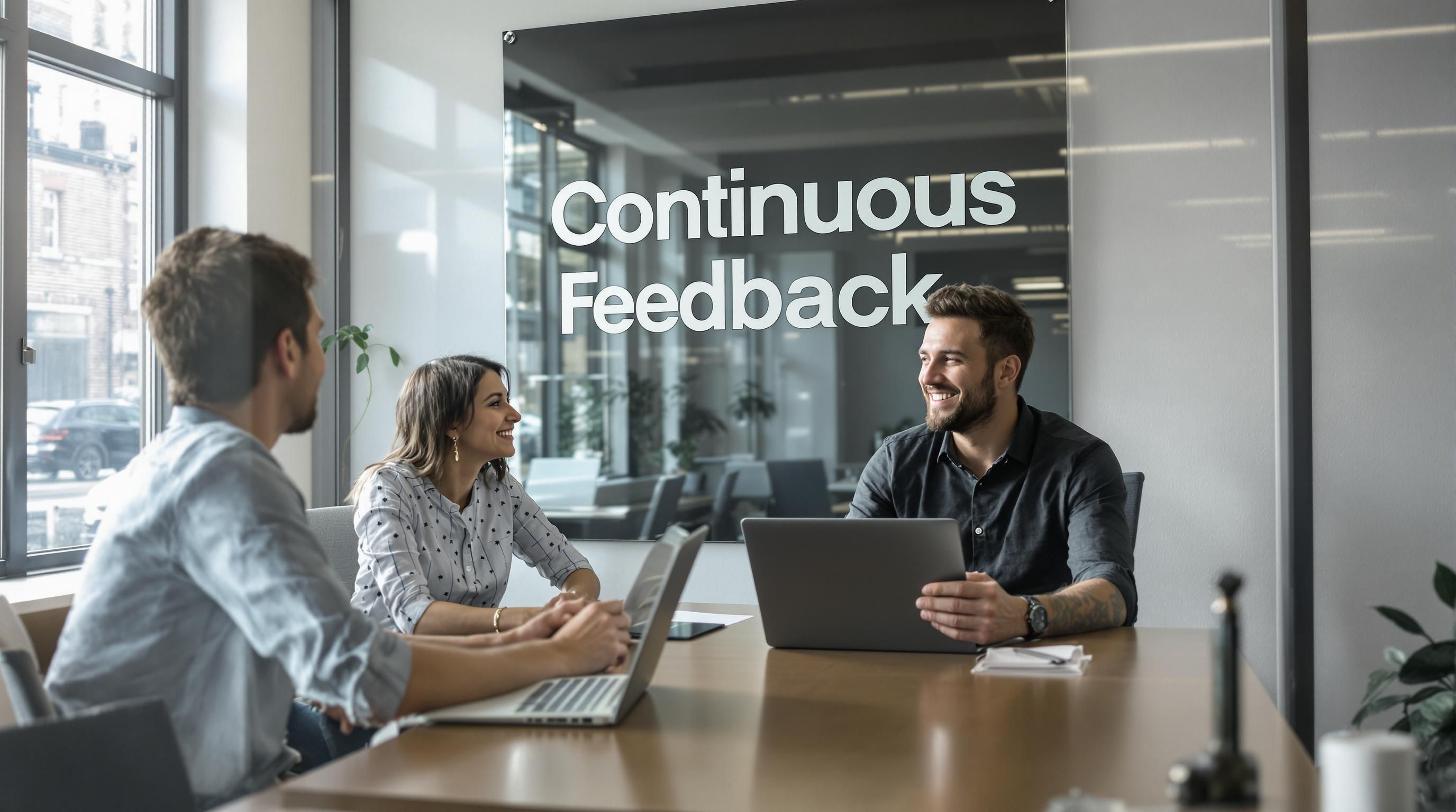 Manager and employee in feedback session, 'Continuous Feedback' poster visible