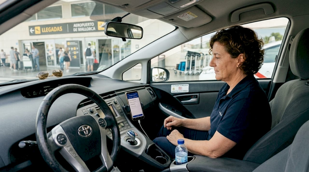 Una taxista está esperando que le llegue una reserva en el aeropuerto de Mallorca.