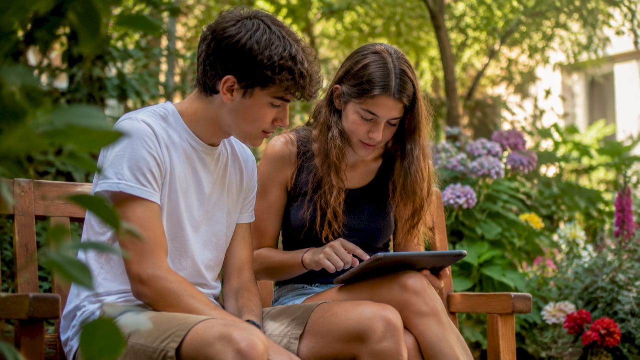 Due ragazzi lavorano insieme in classe utilizzando un tablet per un progetto scolastico.