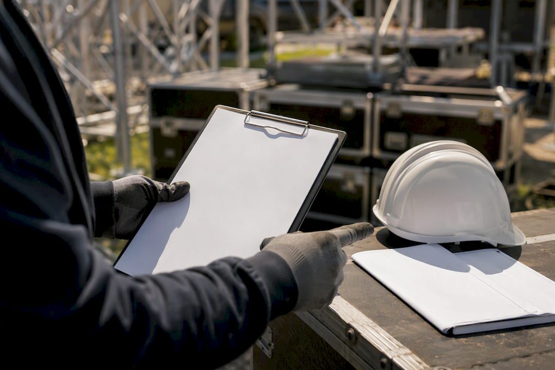 Mani con un blocco per appunti vicino a un casco di sicurezza e a dei progetti