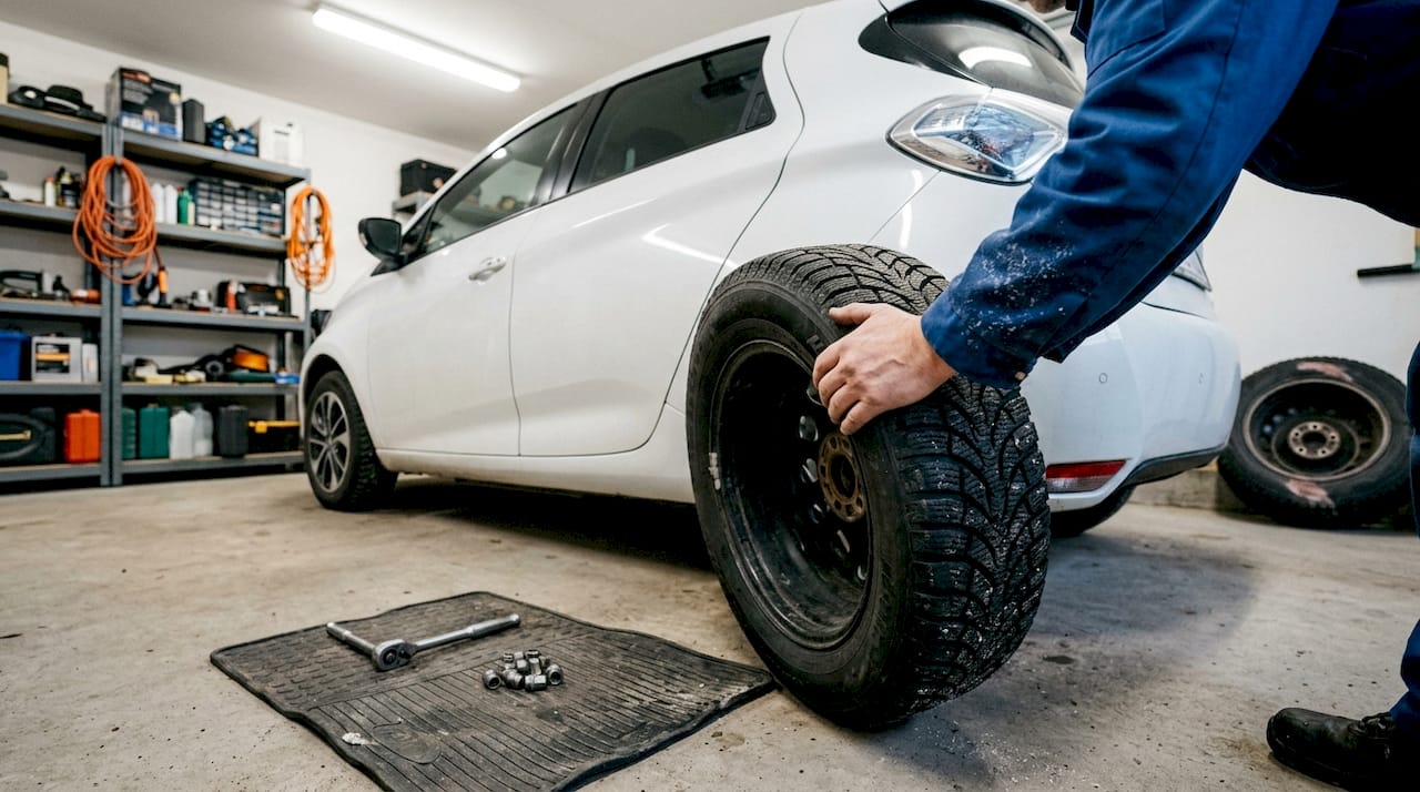 Automekaanikko vaihtaa autoon vahvistetun talvirenkaan.