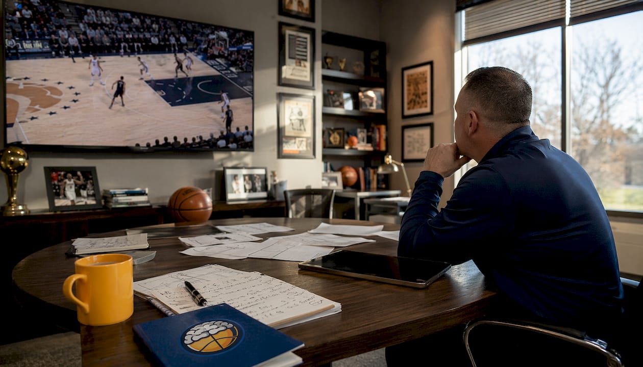 Coach reviewing basketball game footage at desk
