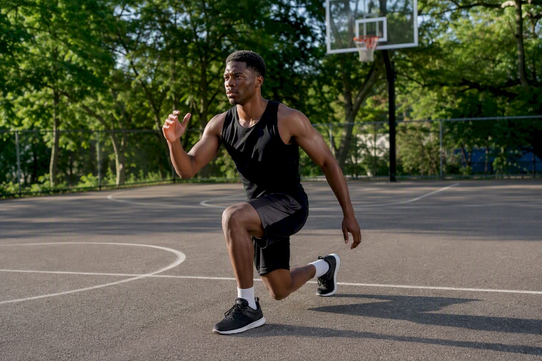 Player performing dynamic warm-up lunges on basketball court