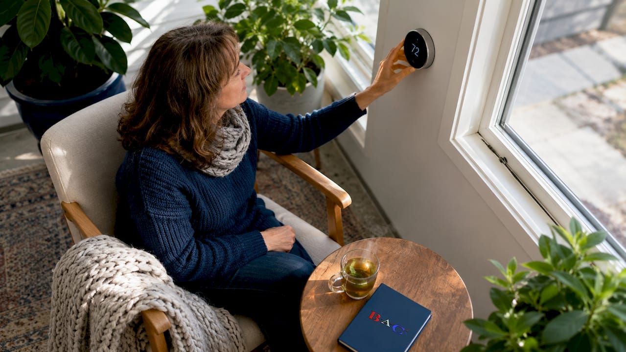 Woman adjusting smart thermostat at home