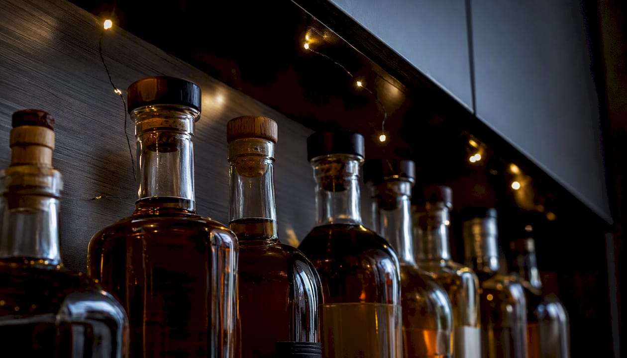 Whisky bottles stored upright in dark wooden cupboard