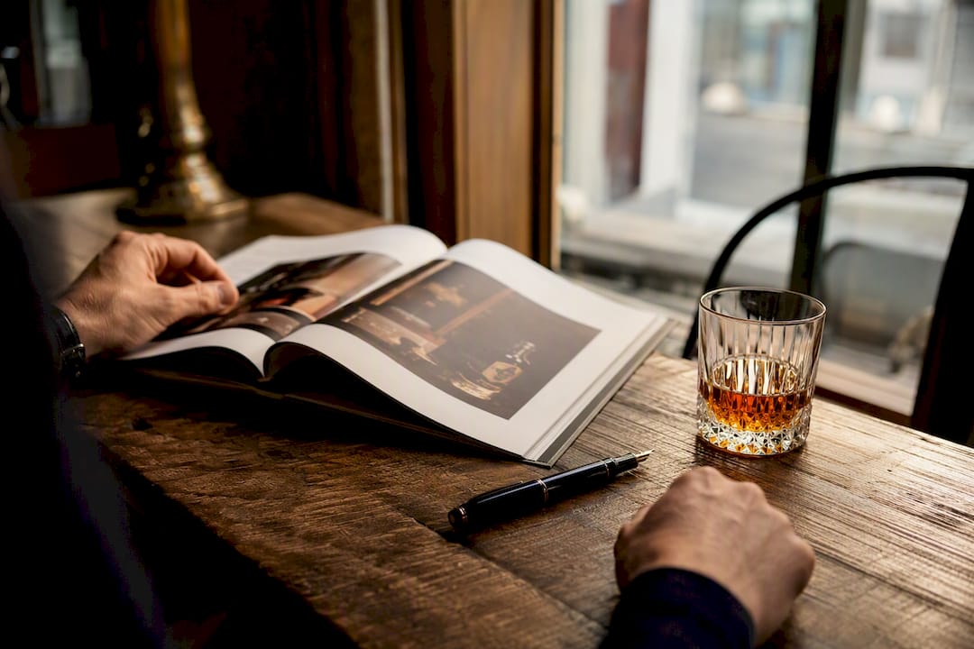 Whisky auction catalog with glass and pen