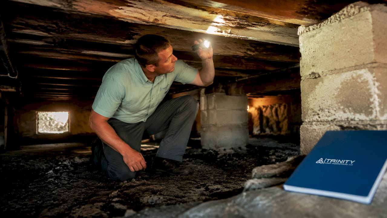 Home inspector examining soft floor in crawlspace