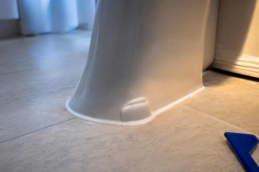 Caulked toilet base with rear gap