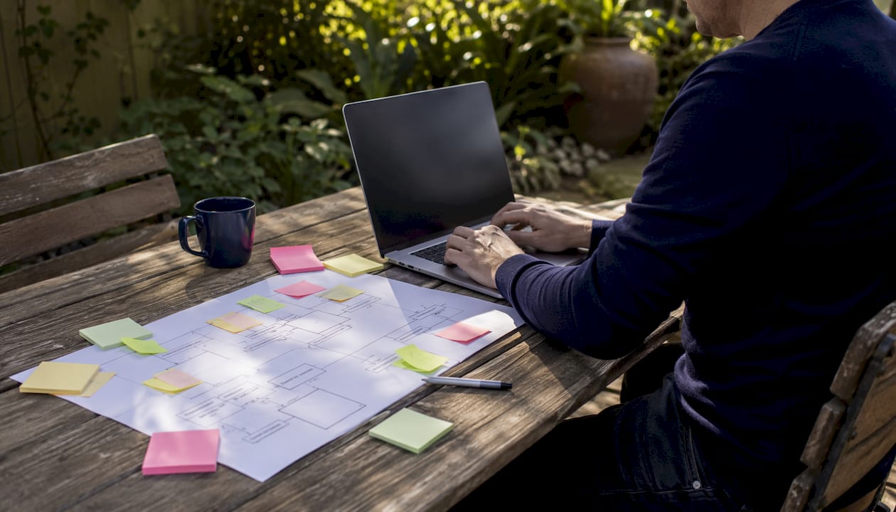 Hands typing on laptop with sitemap and agency tools on desk