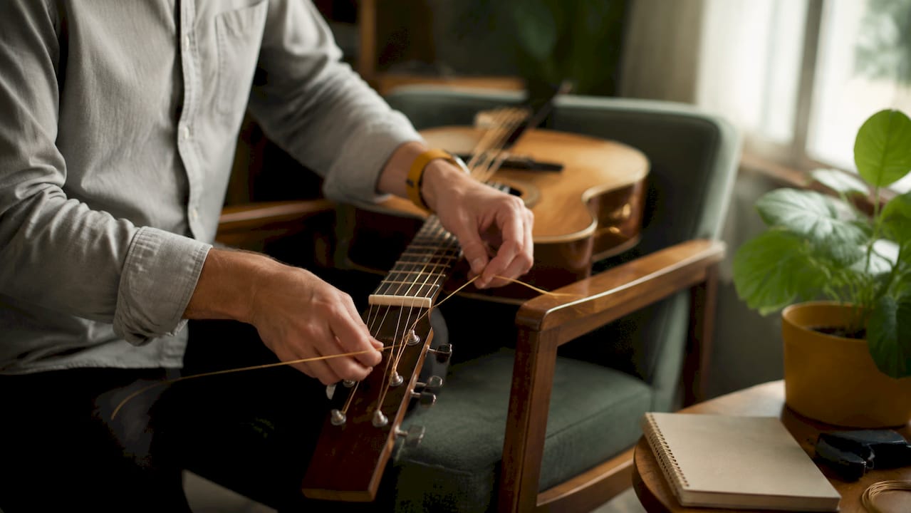 Close-up of hands installing acoustic guitar strings