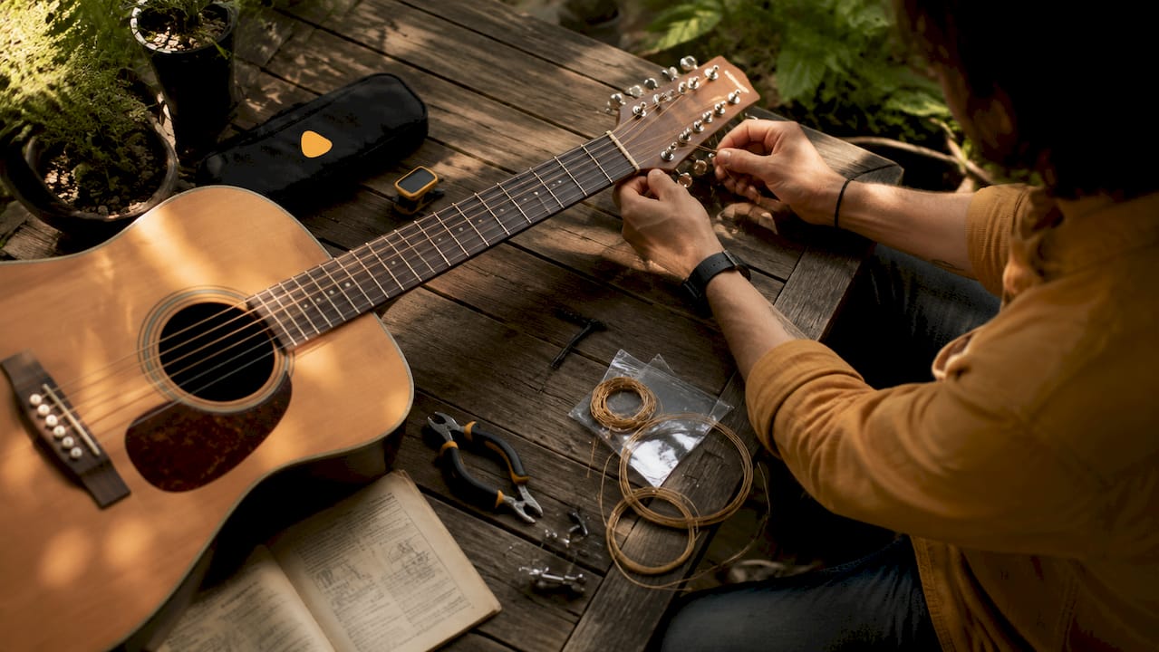 Hands stringing a 12-string guitar at bench