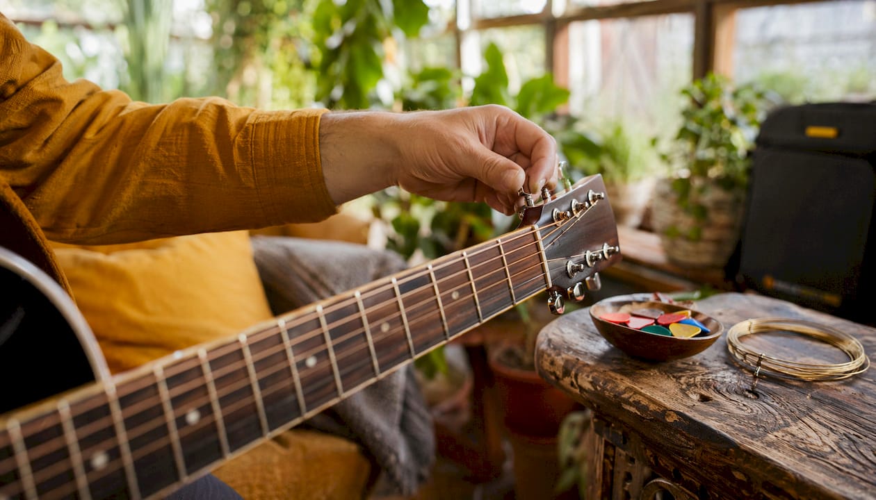 Closeup of hand adjusting electric guitar tuning pegs