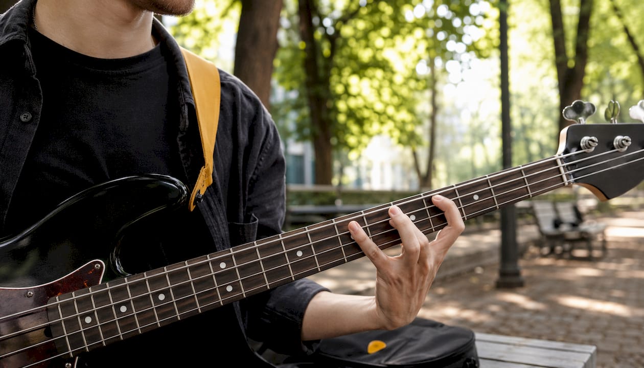 Fingers pressing bass guitar frets closely