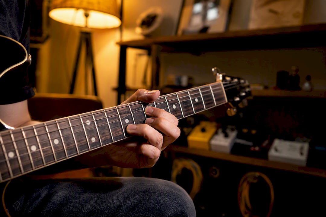 Hand bending guitar string on fretboard