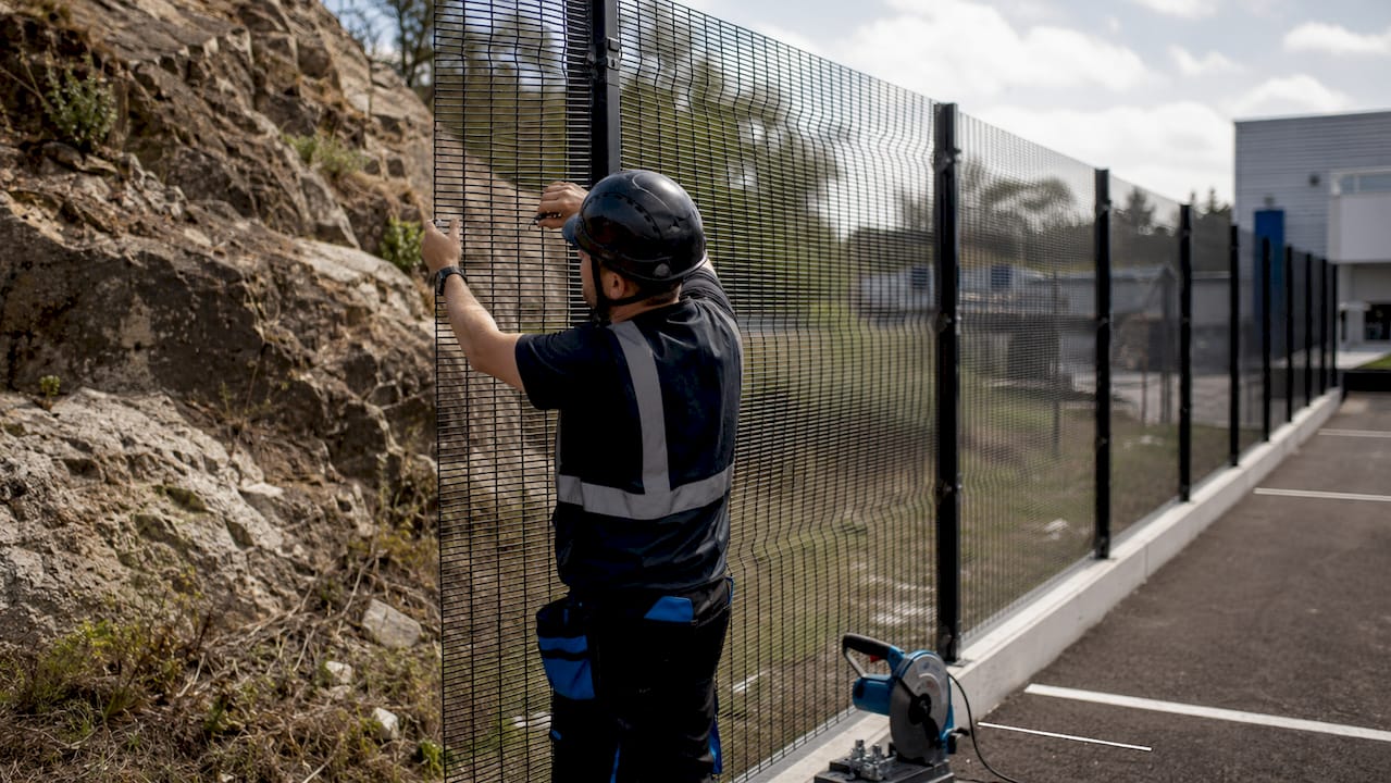 Technician installing anti-climb perimeter fencing