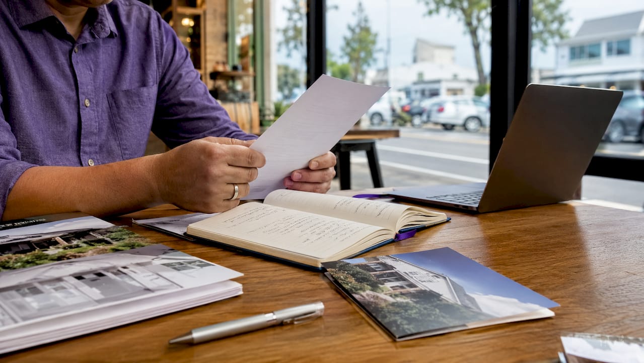 Hands holding proof of funds letter on real estate desk