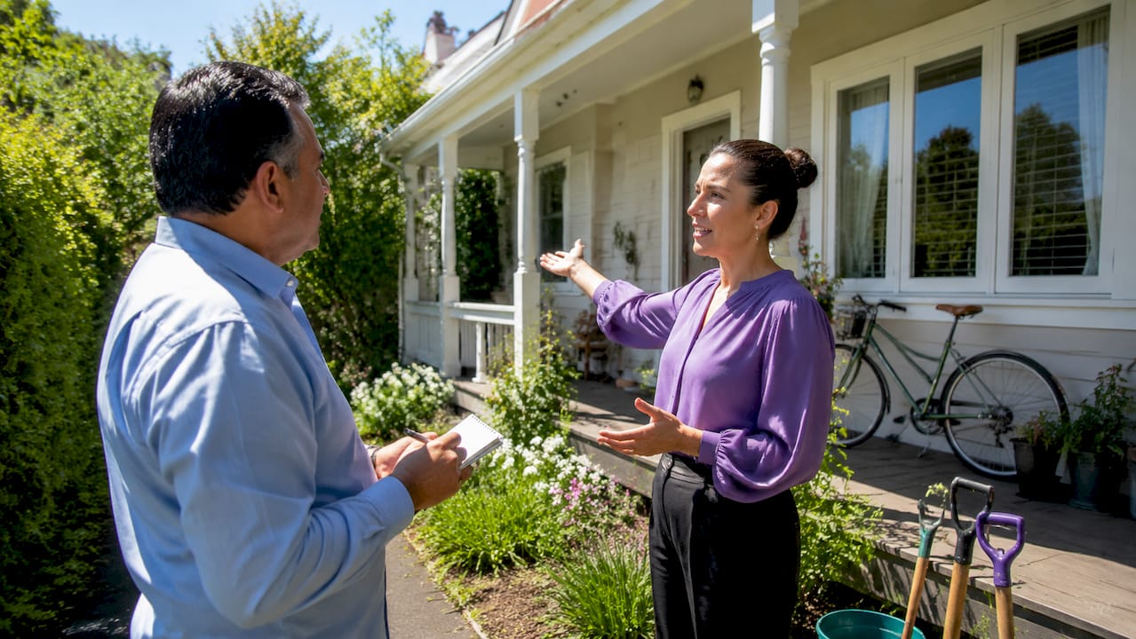 Agent and homeowner discussing home sale preparations outdoors
