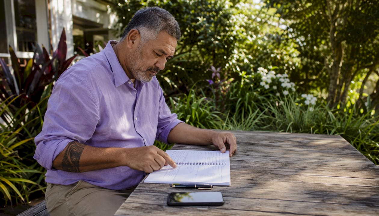 Maori man reviewing property expenses ledger