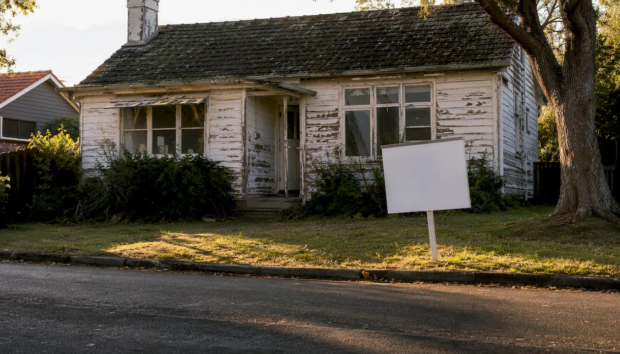 Damaged NZ house with as-is sale sign