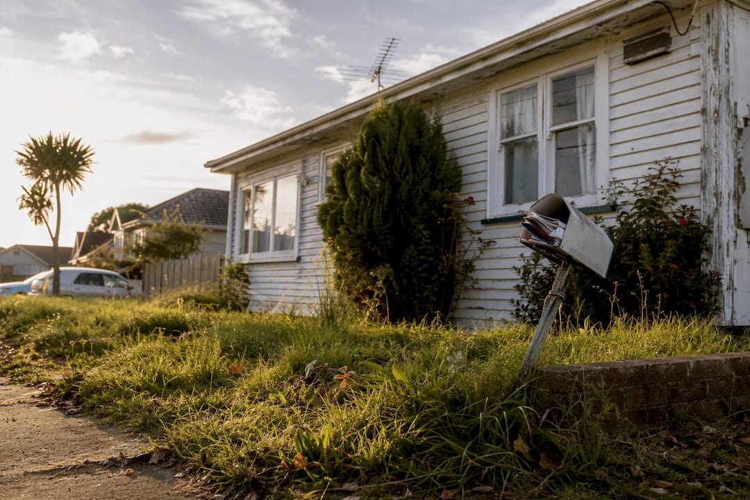 Distressed NZ house exterior with overgrown lawn