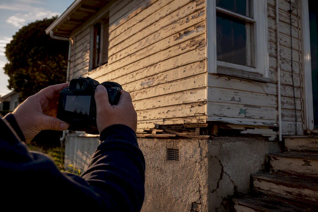 Hands photographing house damage