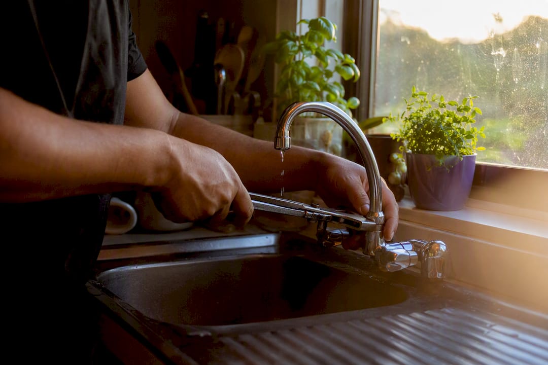 Hands fixing a dripping tap at NZ home