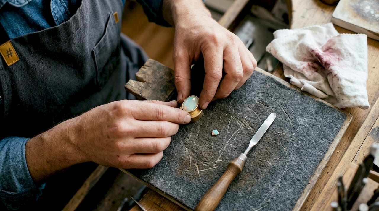 Hands setting opal gemstone in bezel cup