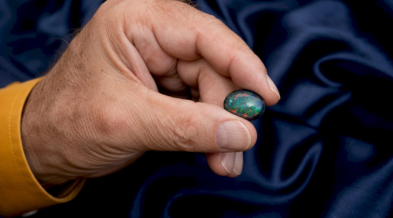 Close-up of hand holding polished black opal