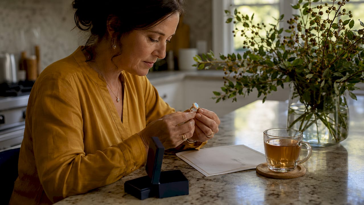 Woman examining opal ring and warranty document
