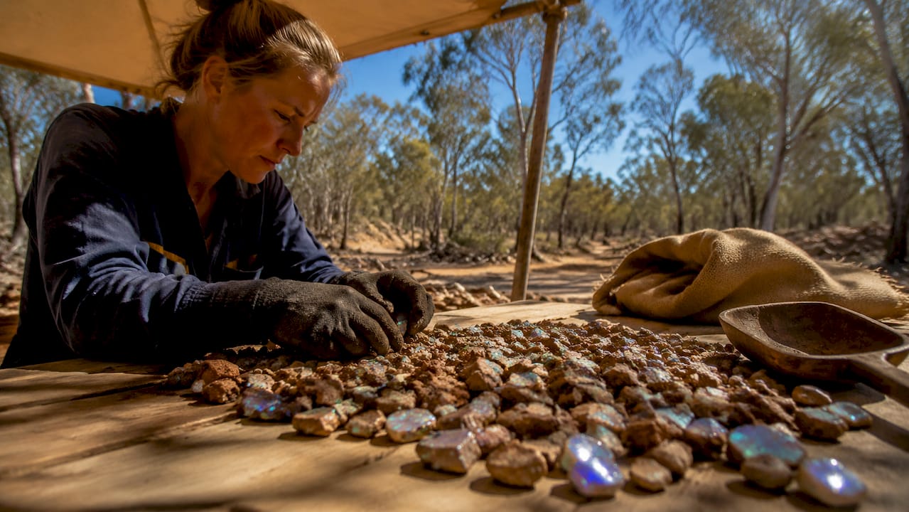 Close-up hands sorting rough opal stones on table
