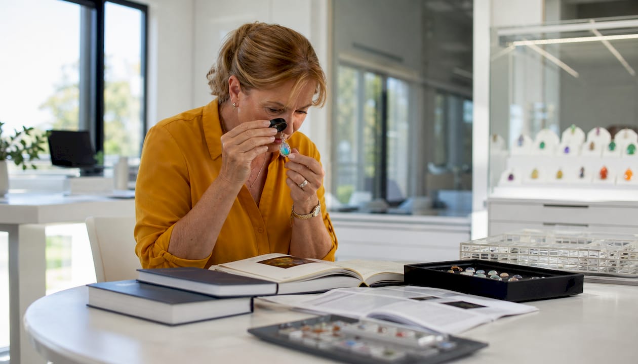 Jewelry collector examining opal pendant with loupe