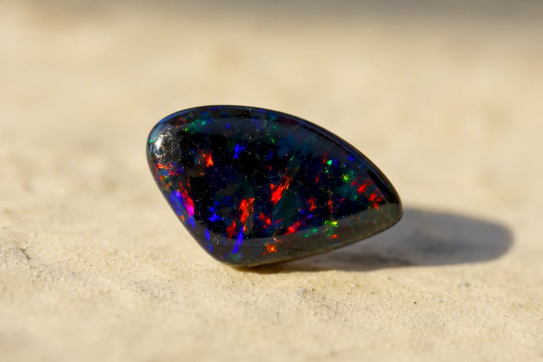 Black opal stone under light showing dark body tone