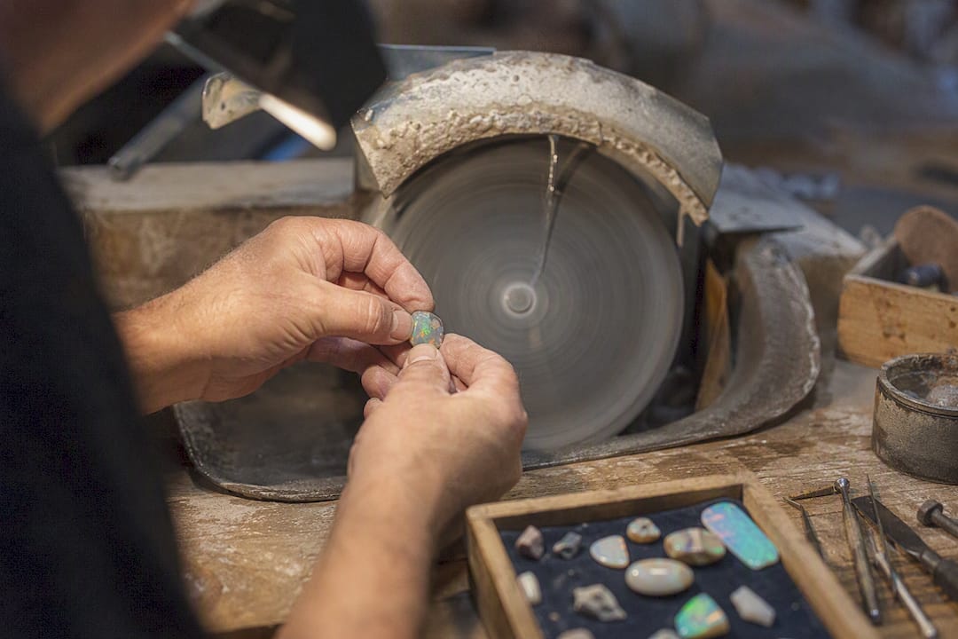 Hands polishing opal cabochon dome