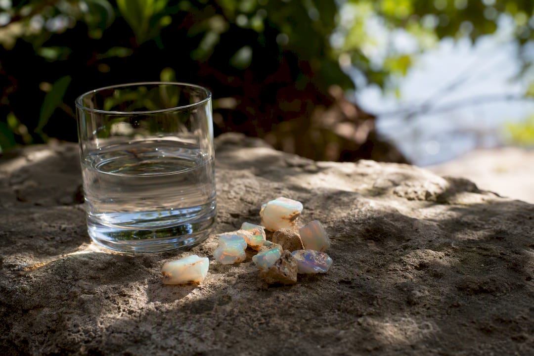 Glass of water next to Australian opal stones indoors