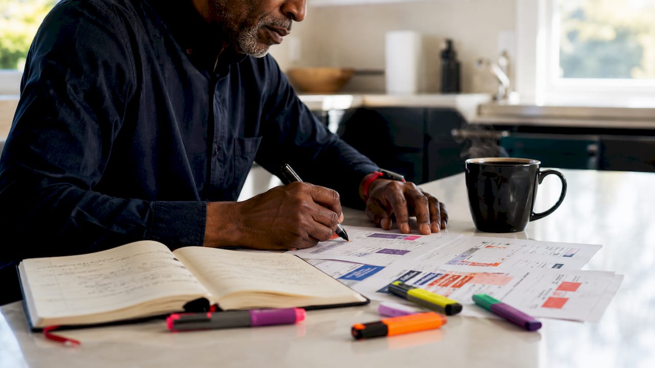 Hands annotating keyword research documents on desk