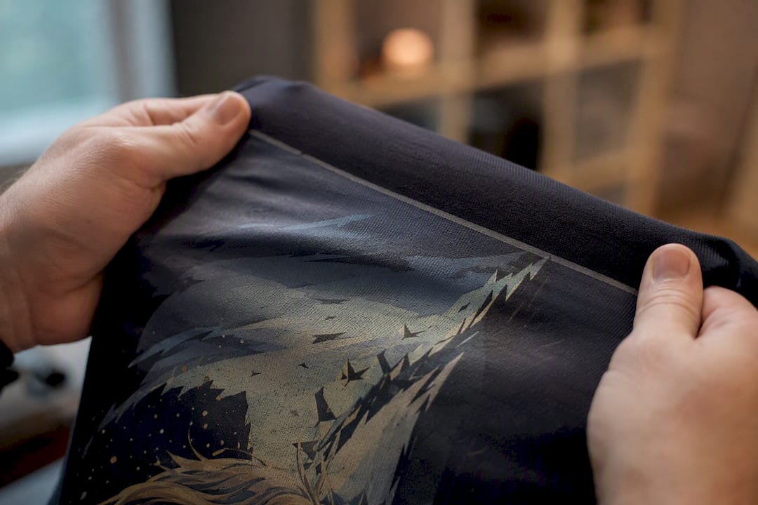 Hands stretching t-shirt fabric showing transfer print edge