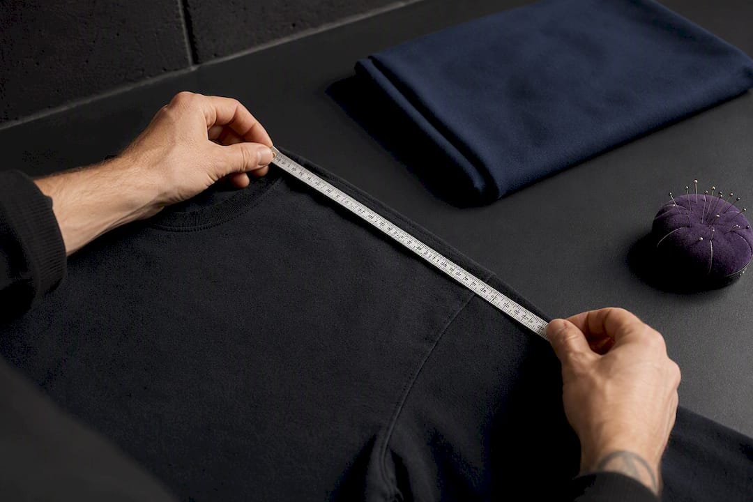 Hands measuring a tee shoulder seam