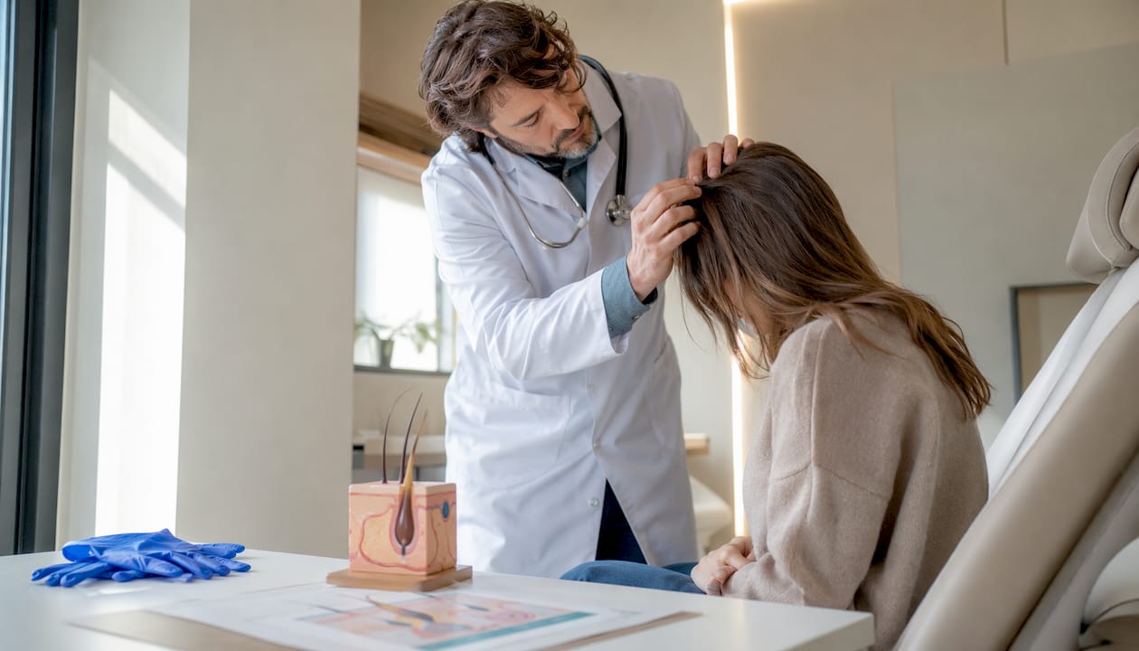 Ein Arzt wirft einen genauen Blick auf die Kopfhaut einer Patientin.