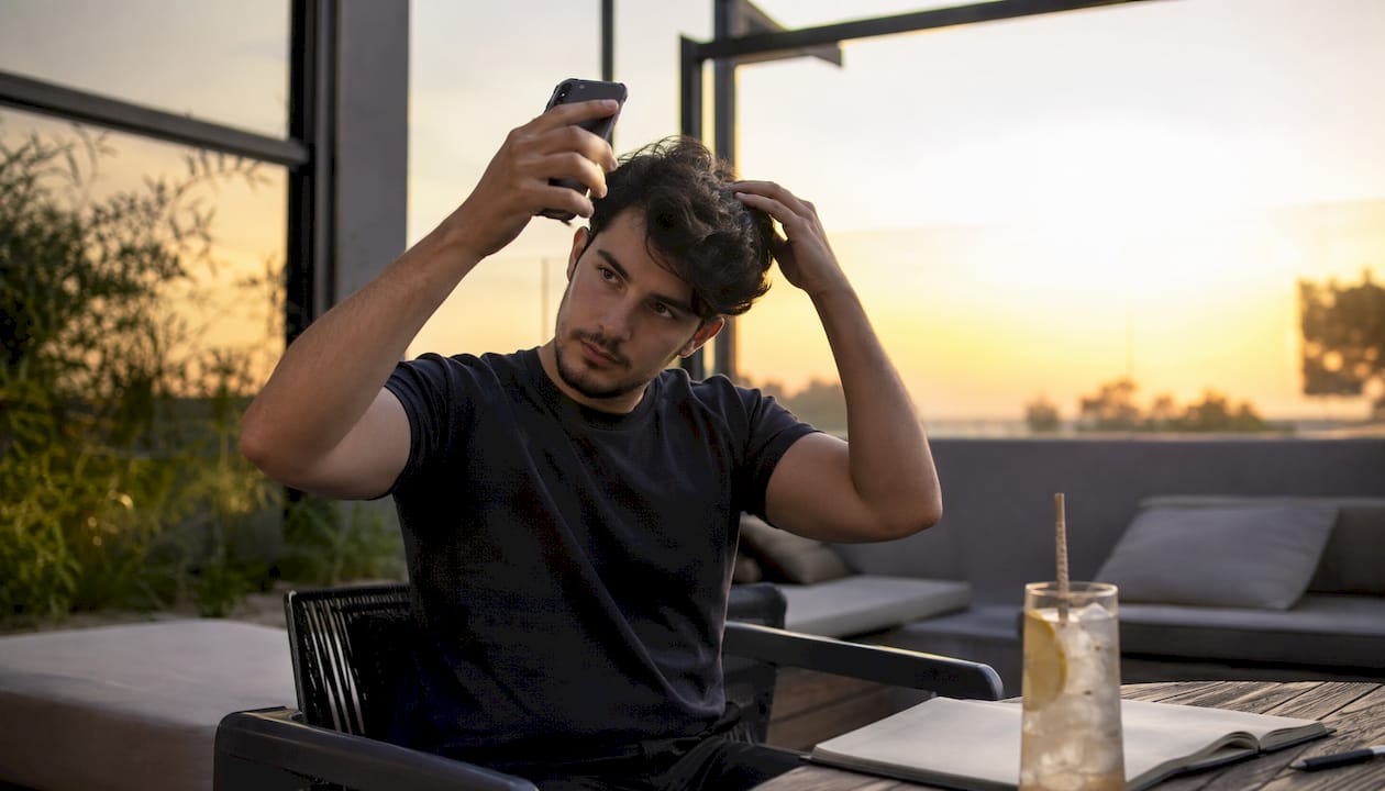 Persona utilizando una aplicación móvil para analizar su cabello