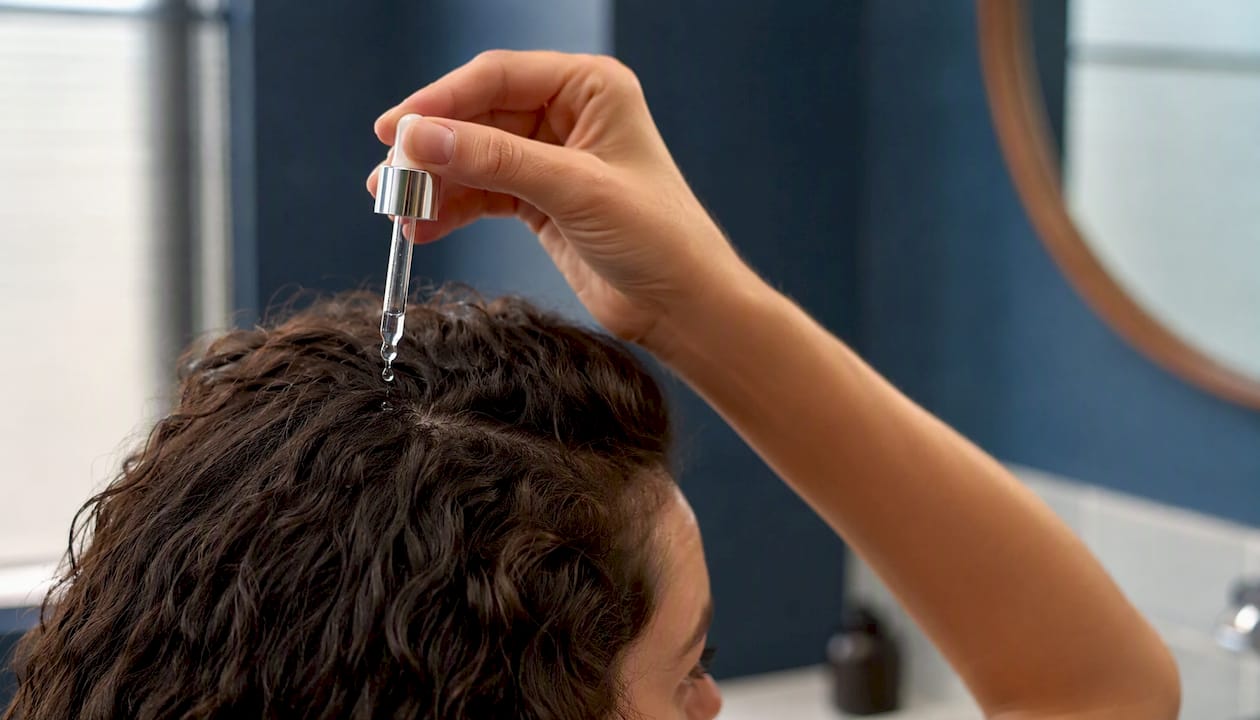 Mit der Hand wird ein Haarserum sanft auf die Kopfhaut einmassiert.