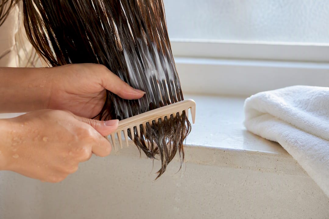 Ein grobzinkiger Kamm verteilt den Conditioner im Haar