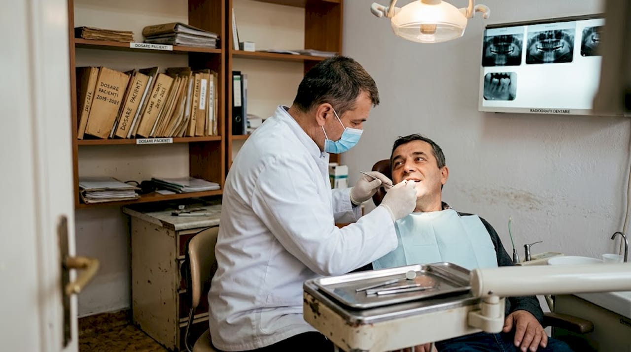 Medicul dentist îi face un consult pacientului aflat pe scaunul stomatologic.