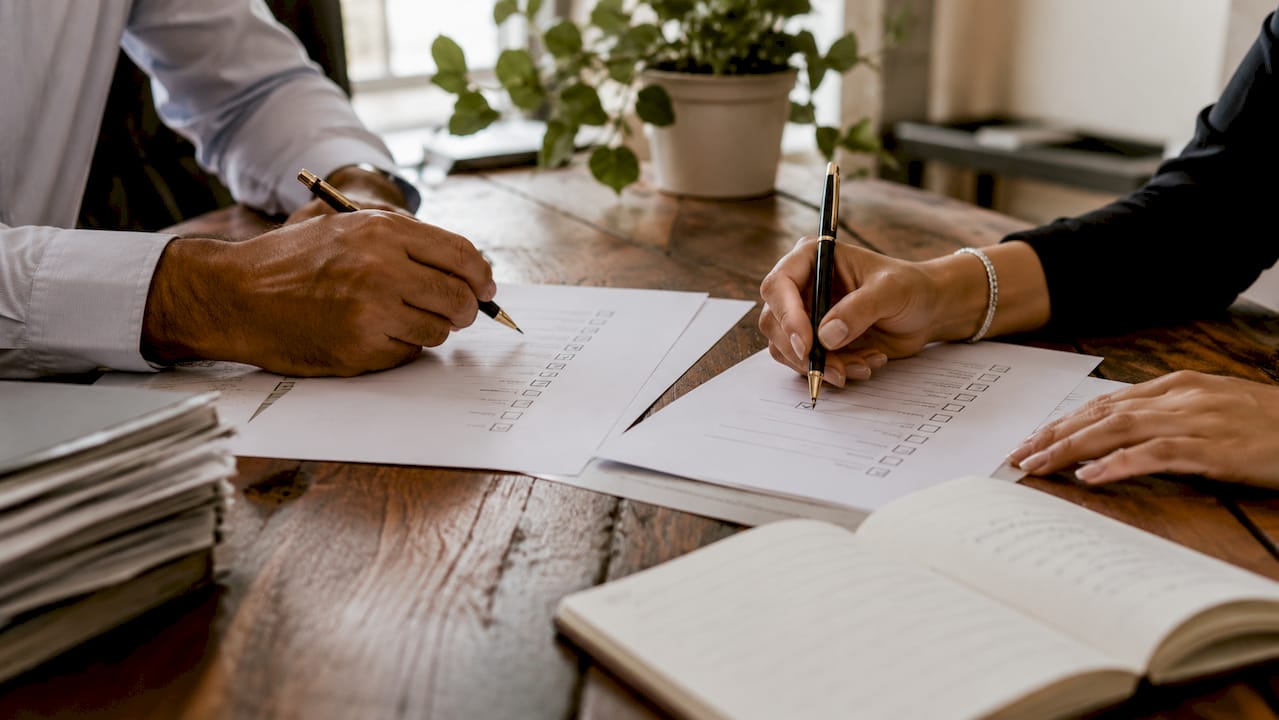 Hands marking internal controls checklist on paper